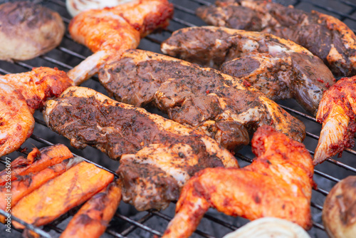 beef marinated steaks and chicken wings are cooked on the grill, barbecue