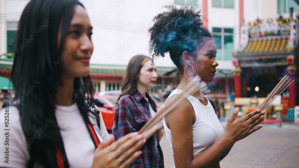 A group of multi-ethnic female friends praying at a Chinese shrine in Bangkok, Thailand. A group of multi-ethnic female friends praying at a Chinese shrine in Bangkok, Thailand.