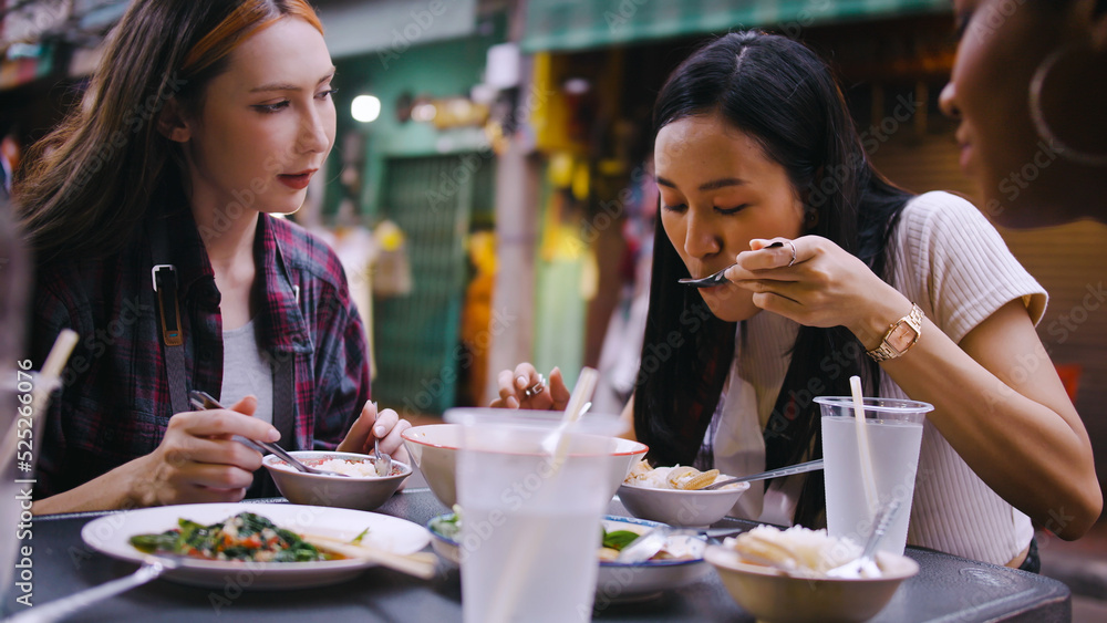 A group of multi-ethnic female friends enjoying street food on Yaowarat Road or Chinatown in Bangkok, Thailand.