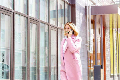 A woman with short brown hair walks around the city and talks on the phone in the spring