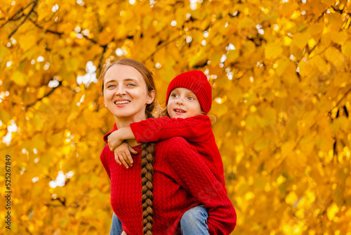 happy mother and child in knitted red clothes play and laugh on an autumn walk