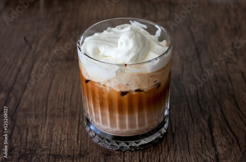 Glass with Ice Mocha with whipped cream. Cold coffee drink on a brown background. 