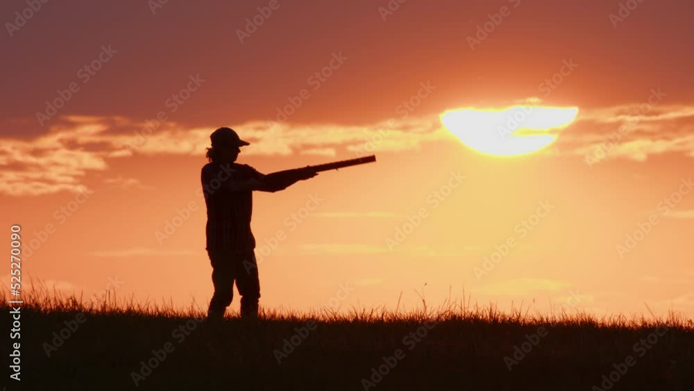 Silhouette of hunter takes aim with shotgun against the sunset sky. Side view. Silhouette of hunter takes aim with shotgun against the sunset sky. Side view.