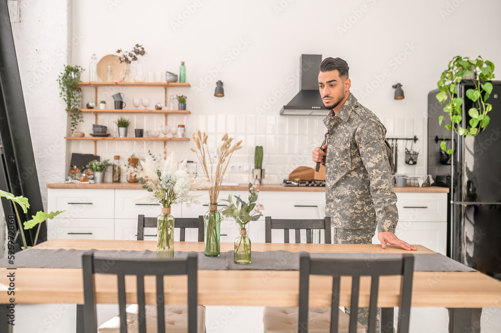 Low-spirited young soldier saying good-bye to his domestic life Low-spirited young soldier saying good-bye to his domestic life