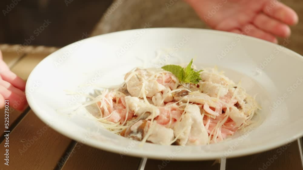 Serving pasta with pink noodles, chicken breast and parmesan cheese in white plate close-up. Italian food dish.