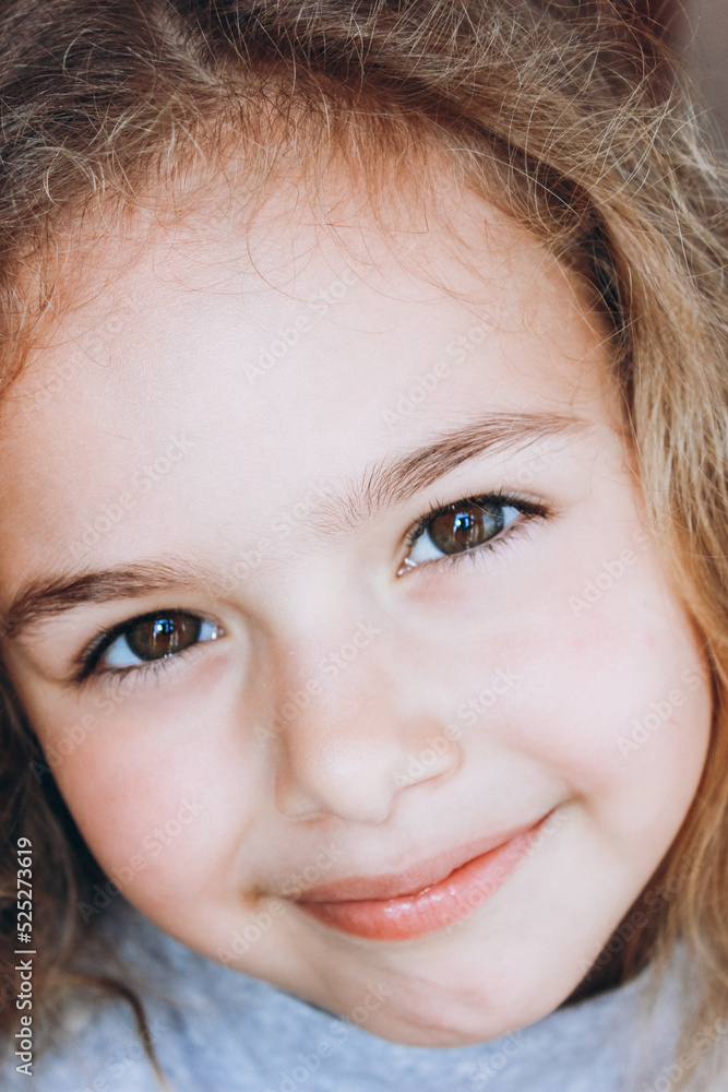 Portrait of a beautiful smiling little girl. Pretty child with blond curly hair looking to camera close-up Portrait of a beautiful smiling little girl. Pretty child with blond curly hair looking to camera close-up