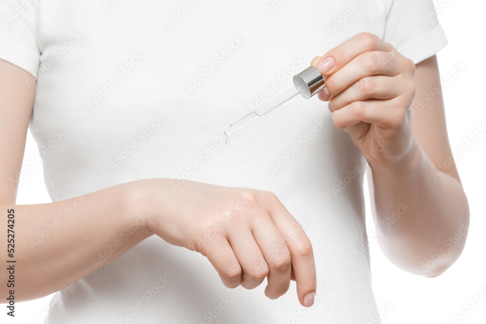 Cropped shot of a woman in white t-shirt holding a pipette with serum, isolated on white. Nice short natural nails.
