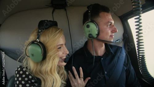 Young couple flying in helicopter.Man and Woman sitting in the cabin of Chopper.Looking out the window while flying in an airplane.People in helicopter.