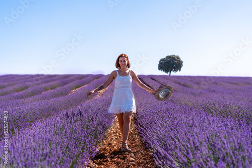 Lifestyle of a woman smiling in a summer lavender field wearing a white dress