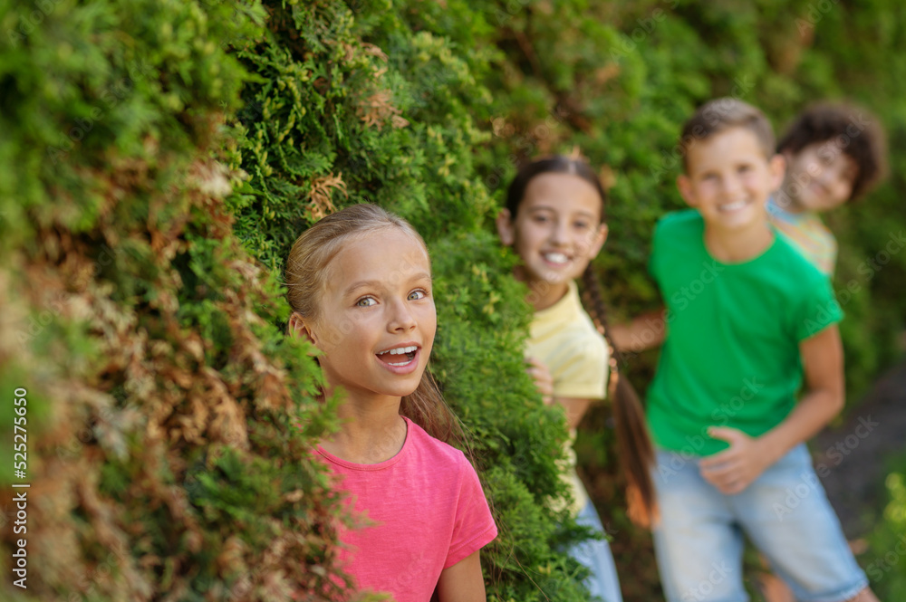 Happy girl and friends looking out of bushes Happy girl and friends looking out of bushes
