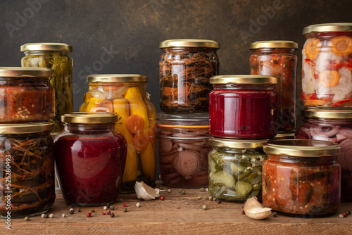 Preserving vegetables for the winter, canned vegetables in jars on a wooden table against a brown wall, pickled or fermented vegetables, copy space