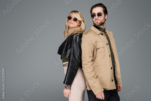 blonde woman and bearded man in sunglasses posing together isolated on grey