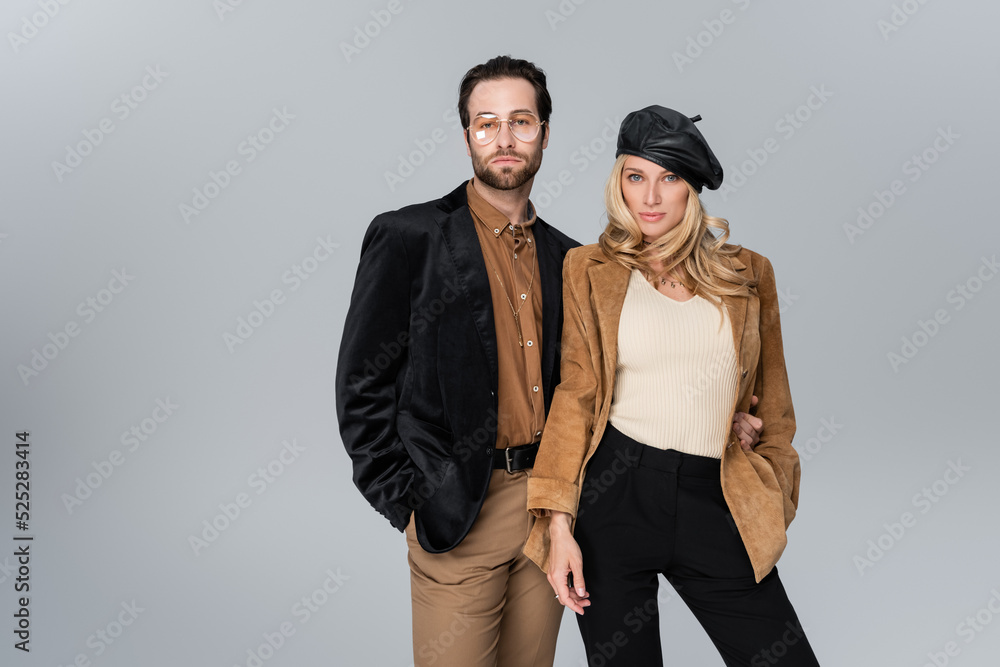 blonde woman in stylish beret posing with bearded man in sunglasses isolated on grey blonde woman in stylish beret posing with bearded man in sunglasses isolated on grey