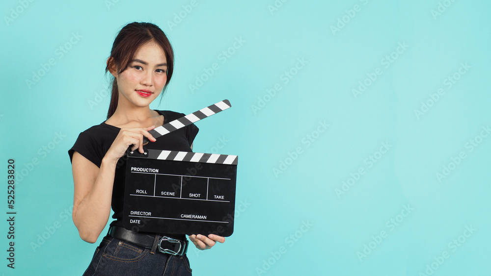 Woman holding black clapperboard or movie slate on green mint or Tiffany Blue background.