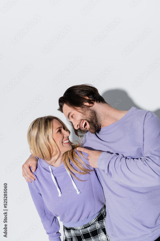 happy bearded man in purple sweatshirts pointing at blonde woman on grey happy bearded man in purple sweatshirts pointing at blonde woman on grey