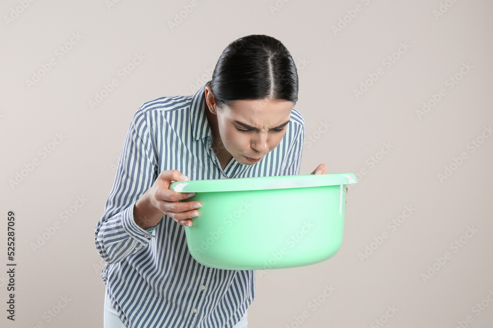 Woman with basin suffering from nausea on beige background. Food poisoning Woman with basin suffering from nausea on beige background. Food poisoning