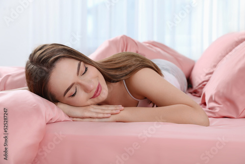 Young woman sleeping on comfortable bed with silky linens