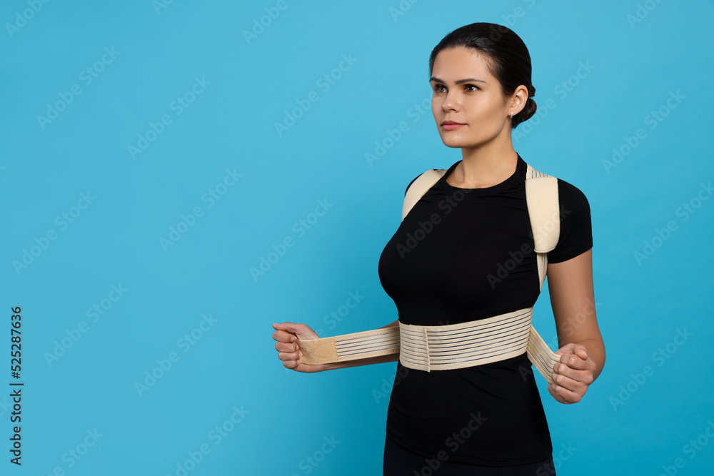 Beautiful woman with orthopedic corset on blue background, space for text Beautiful woman with orthopedic corset on blue background, space for text