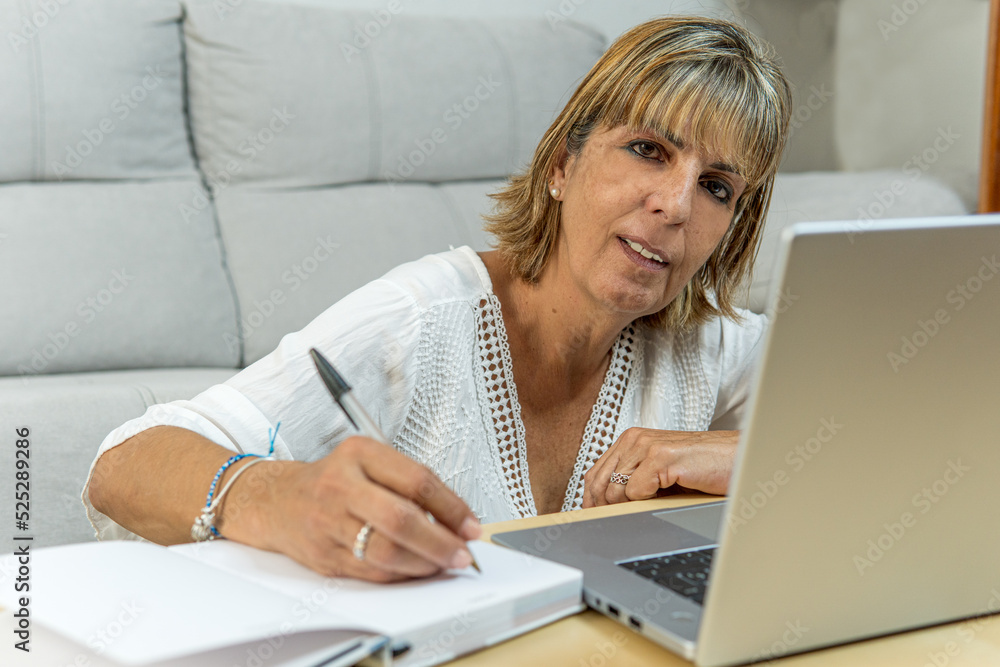 Adult woman writing in her diary looking at the camera Adult woman writing in her diary looking at the camera