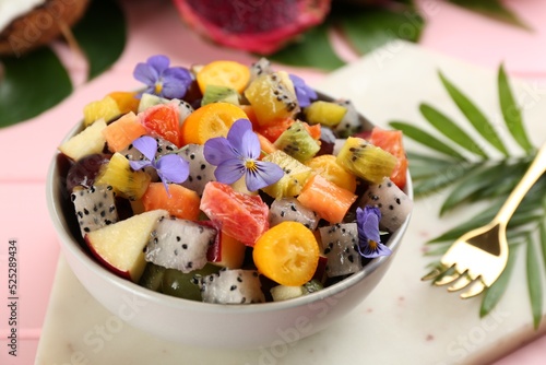Delicious exotic fruit salad served on pink table, closeup