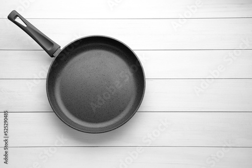 Fototapeta New non-stick frying pan on white wooden table, top view