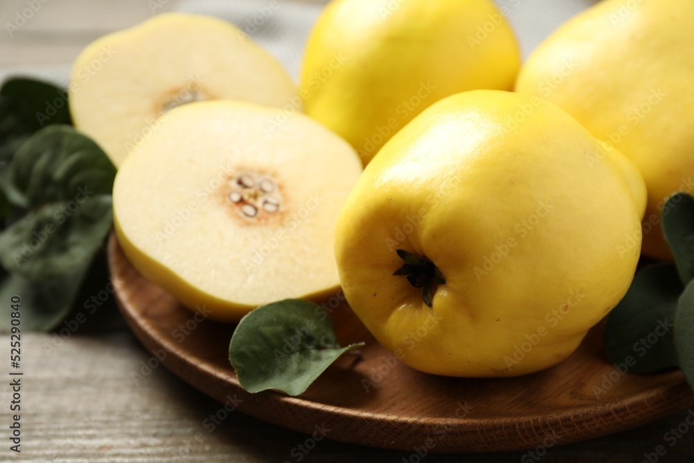 Fresh ripe organic quinces with leaves on wooden table, closeup Fresh ripe organic quinces with leaves on wooden table, closeup