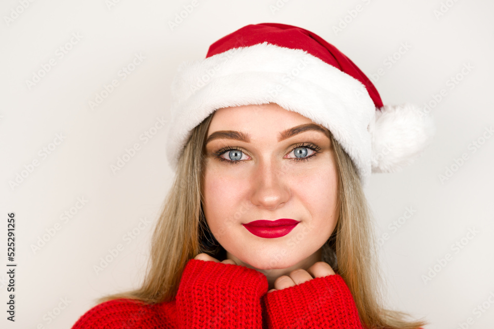 Studio portrait of pretty blonde girl in santa hat and red sweater smiling at camera.Christmas concept Studio portrait of pretty blonde girl in santa hat and red sweater smiling at camera.Christmas concept