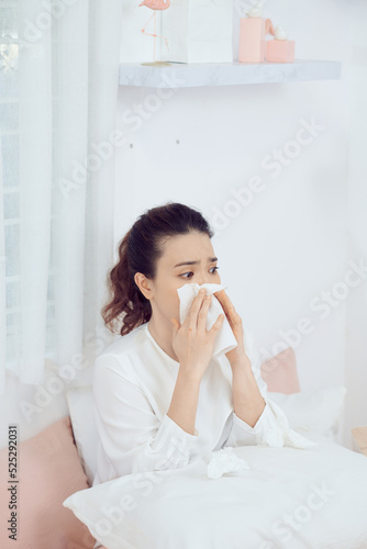 Asian woman feeling unwell and sneeze on bed