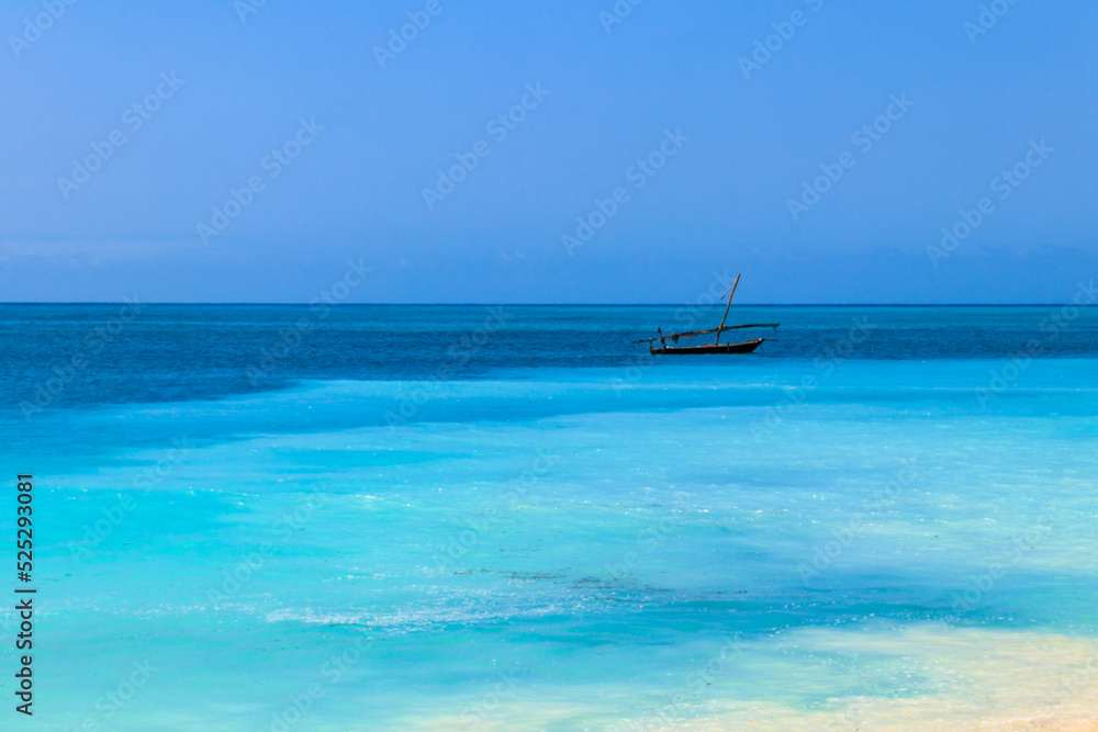 View of tropical sandy Nungwi beach and traditional wooden dhow boat in the Indian ocean on Zanzibar, Tanzania View of tropical sandy Nungwi beach and traditional wooden dhow boat in the Indian ocean on Zanzibar, Tanzania