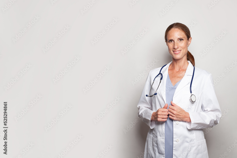 Pretty woman doctor hospital worker looking at camera and smiling against grey studio wall banner background Pretty woman doctor hospital worker looking at camera and smiling against grey studio wall banner background