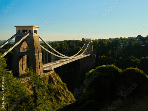 The famous Clifton Suspension Bridge at Bristol in dramatic side-lighting from a setting summer sun.