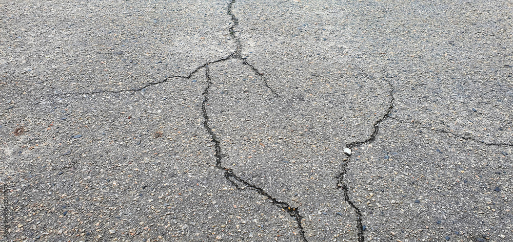 Fototapeta premium Cracks in the asphalt. An old road with cracked asphalt. The road needs repair