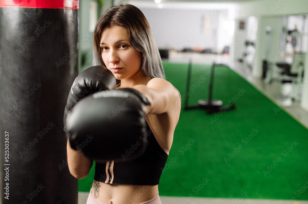 Sport fitness adult girl wearing a boxing gloves in the gym