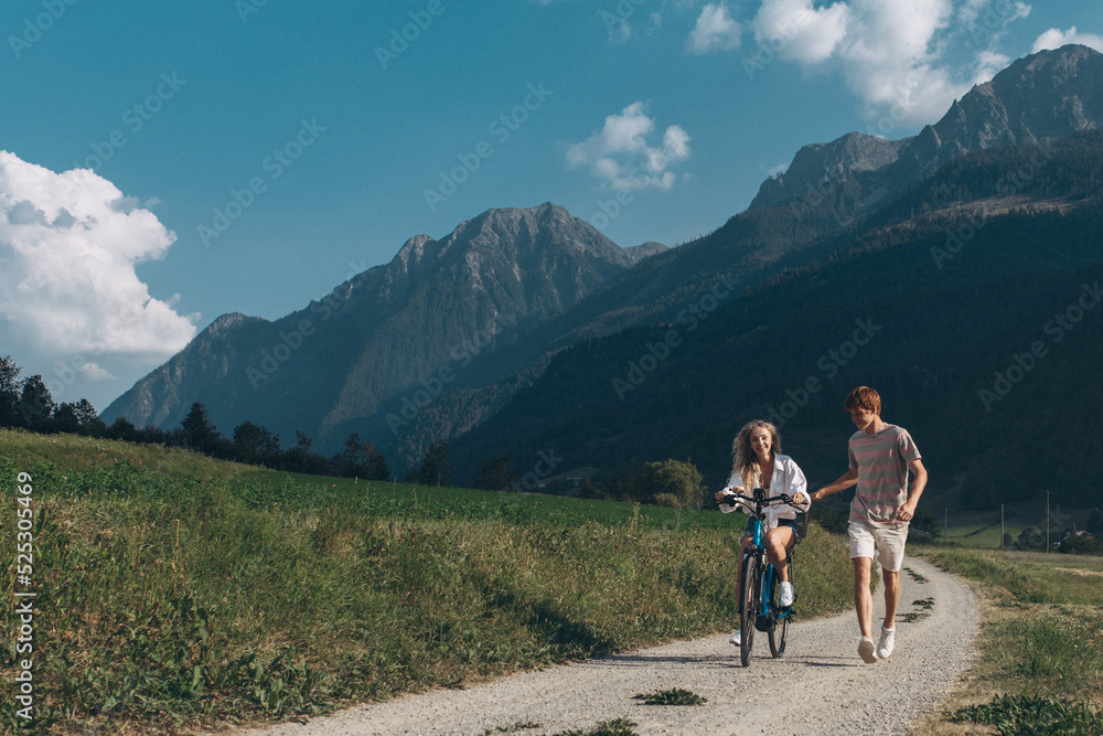 Two friends are cycling along the road. Sport and active life sunset time concept. Couple learning to ride a bike, having fun together, traveling in the mountains in the city