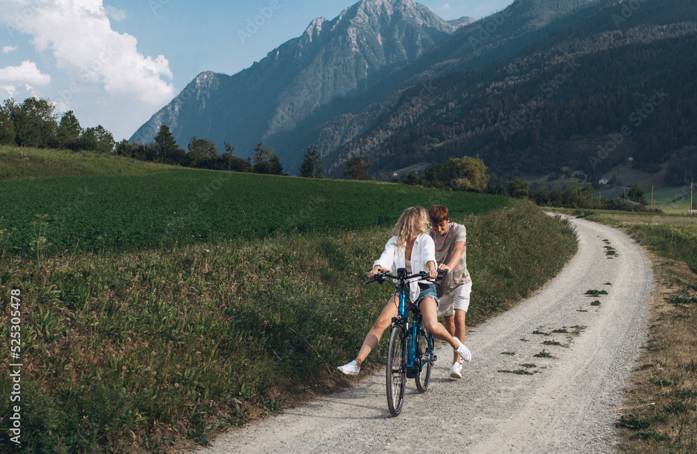 Two friends are cycling along the road. Sport and active life sunset time concept. Couple learning to ride a bike, having fun together, traveling in the mountains in the city