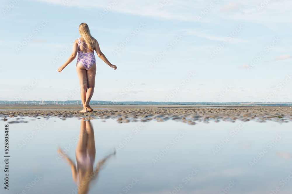 in a swimsuit image of a full length teenager girl posing from behind, enjoying the amazing ocean view, spinning and having fun, relaxing in freedom.