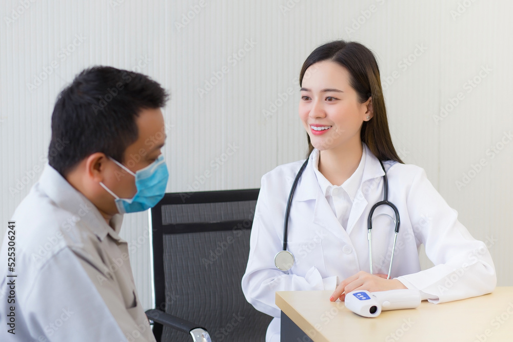 Asian beautiful young woman doctor talking with a man patient about his pain and symptom while they put on a face mask to prevent Coronavirus disease and Thermometer on table in hospital. Asian beautiful young woman doctor talking with a man patient about his pain and symptom while they put on a face mask to prevent Coronavirus disease and Thermometer on table in hospital.