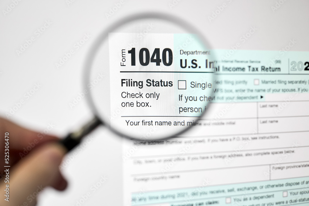 Man looking through a magnifying glass at U.S. Individual Income Tax Return declaration form 1040 Man looking through a magnifying glass at U.S. Individual Income Tax Return declaration form 1040