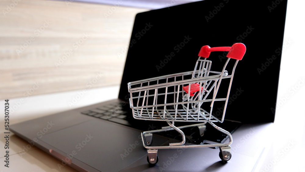 Shopping cart with laptop on the desk, online shopping concept.