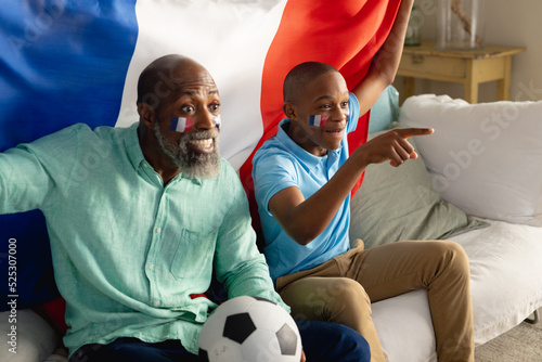 Happy african american male teenager with his father supporting with flag of france