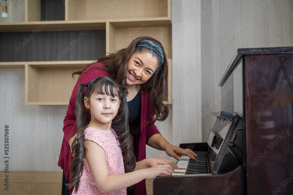 Mother teaching daughter to play the piano,Happy child of learning the piano.  foto de Stock | Adobe Stock
