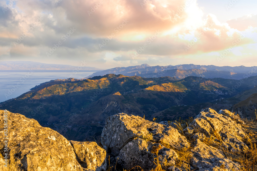 Fototapeta premium amazing mountain landscape of beautiful cloudy sunset above rocks , blue sea and isles with a rock on foreground