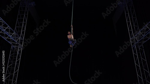 Muscular and fit circus artist perform on aerial rope on high altitude