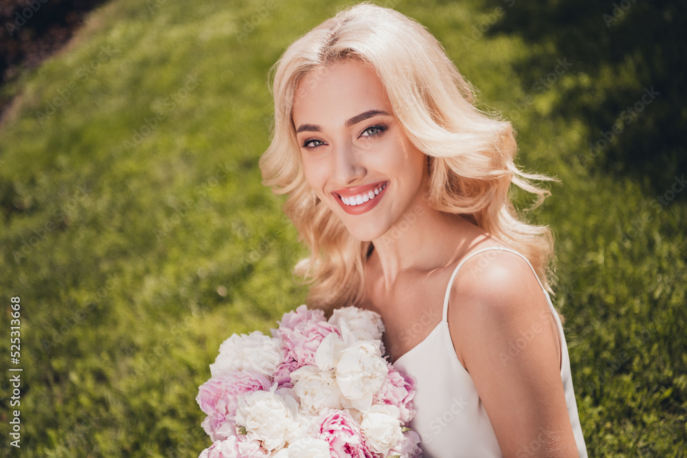 Fototapeta premium Photo of dreamy cute young curly girl dressed white singlet enjoying sunny weather holding bouquet outdoors countryside
