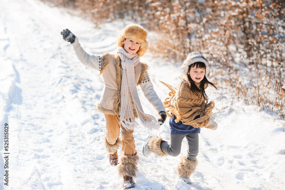 Cheerful children play together in snow in winter. Children run along snowy road.