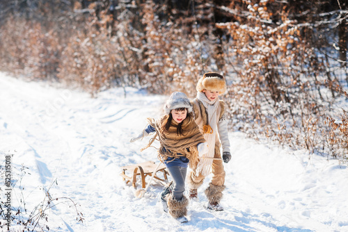 Two happy children are running on snowy road in winter. Family on winter walk.