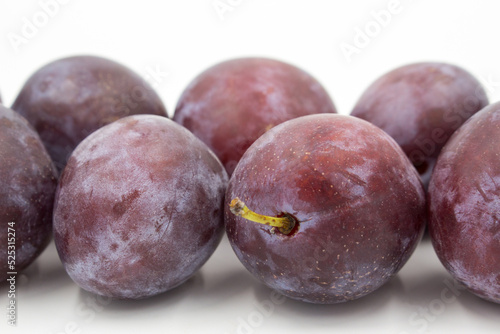 Ripe dark purple plums on a white background.