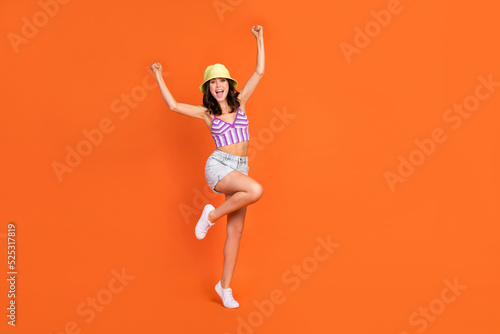 Full size photo of brunette hooray lady yell wear hat top jeans shorts shoes isolated on orange color background