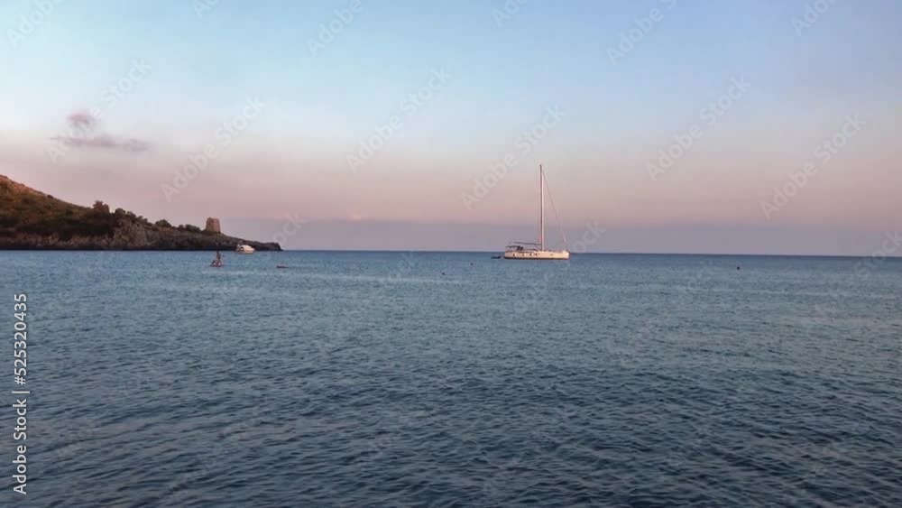 Boat moored and some people enjoying the beach. Sunset over the bay, Marina di Camerota, Italy. Boat moored and some people enjoying the beach. Sunset over the bay, Marina di Camerota, Italy.