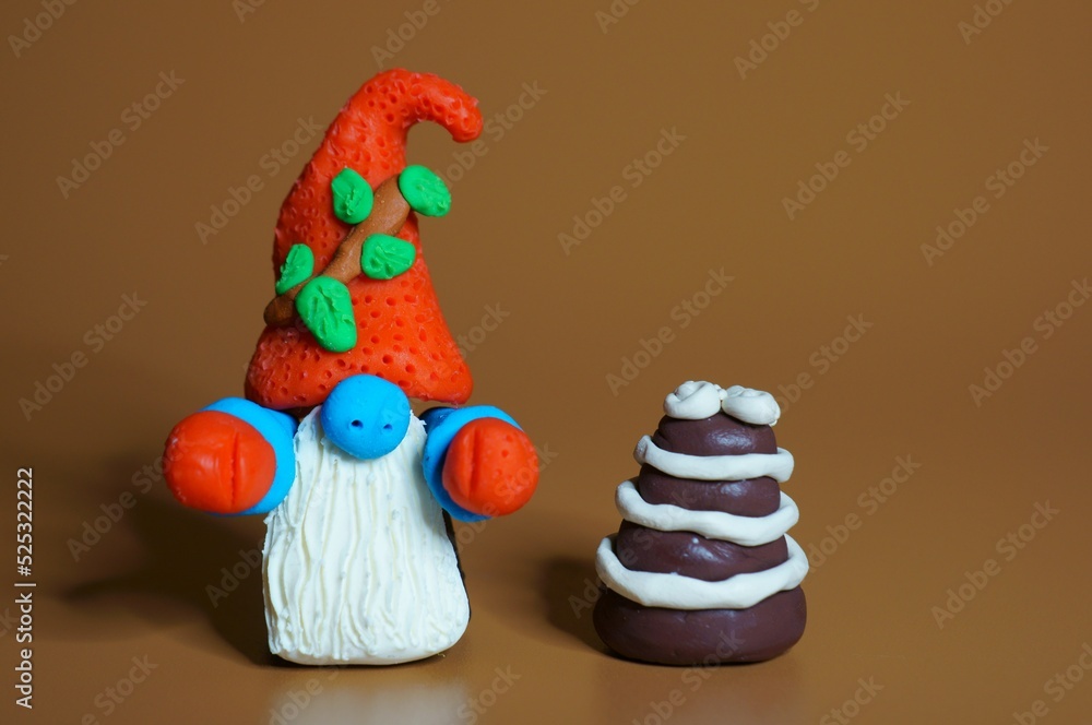 A gnome figurine with a cake on a brown background. Christmas toys and decorations.
